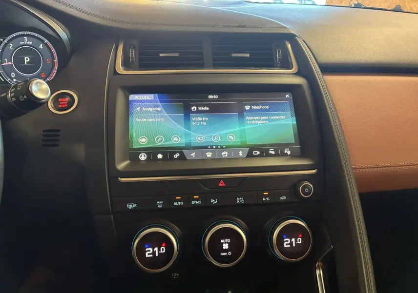 Vue intérieure centrée sur la console centrale du Jaguar E-PACE 2019, avec écran tactile et commandes de climatisation visibles.