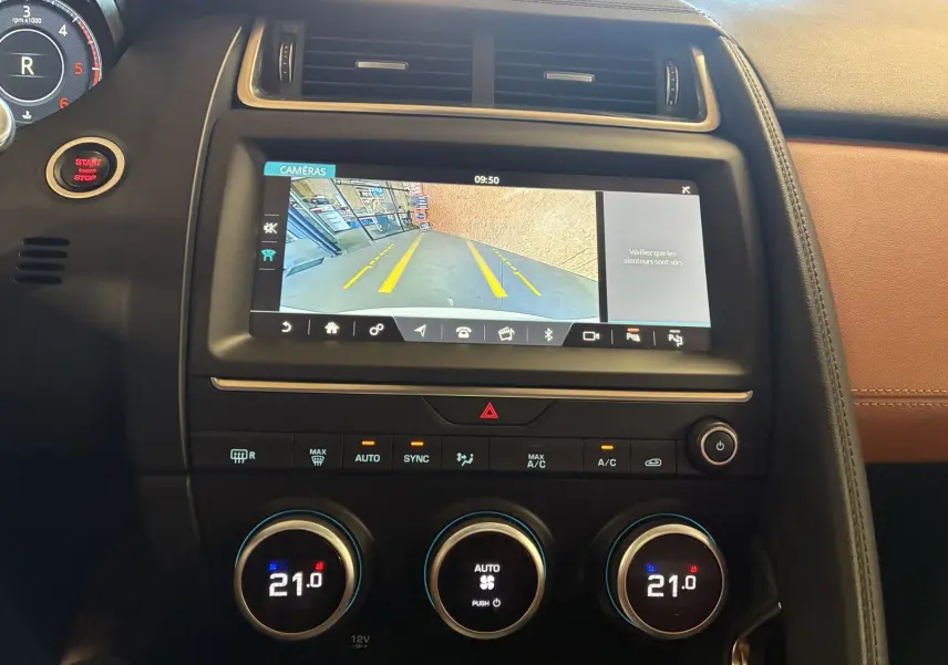 Vue intérieure du tableau de bord du Jaguar E-PACE 2019 avec écran de caméra de recul et commandes de climatisation à 21°C.