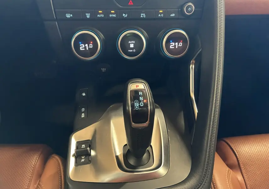 Vue rapprochée de la console centrale du Jaguar E-PACE blanc, mettant en valeur le levier de vitesse automatique et les commandes de climatisation.