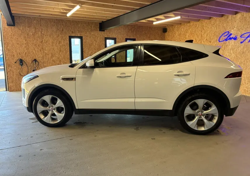 Jaguar E-PACE blanc vue de profil côté gauche, SUV compact avec jantes alliage et vitres teintées en intérieur.