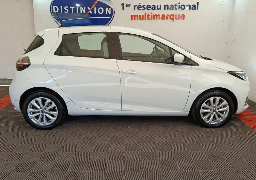 Profil latéral droit d'une Renault ZOE blanche 2021, compacte et électrique, avec jantes alliage et vitres teintées.