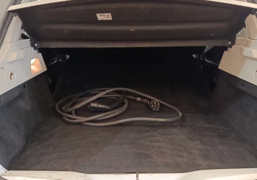 Coffre ouvert d’une Renault ZOE blanche 2021, avec câble de recharge électrique visible à l’intérieur.