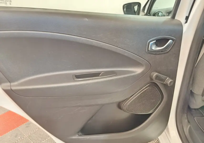 Vue intérieure de la porte arrière droite noire de la Renault ZOE Zen R135 blanche de 2021, avec poignée et manivelle de vitre.