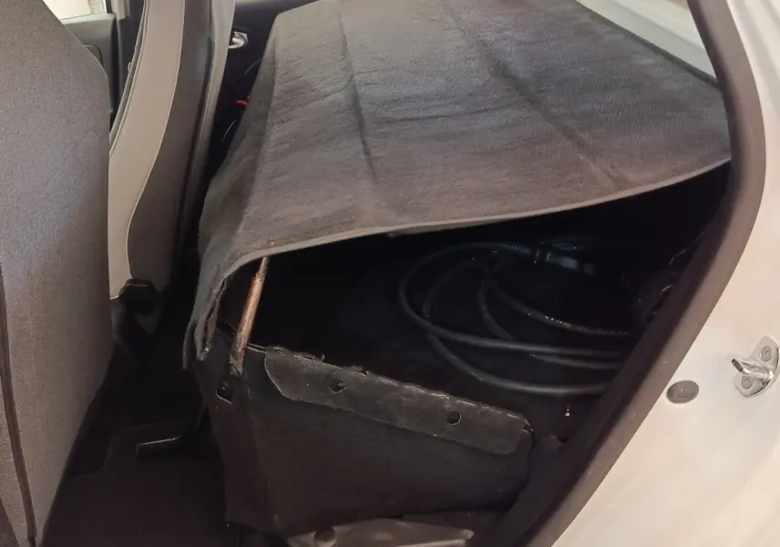 Vue intérieure arrière droite de la Renault ZOE blanche 2021, banquette rabattue avec câble de recharge visible sous une housse.