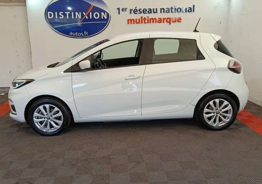 Profil côté gauche d'une Renault ZOE blanche 2021 Zen R135 électrique, avec jantes alliage et vitres teintées.
