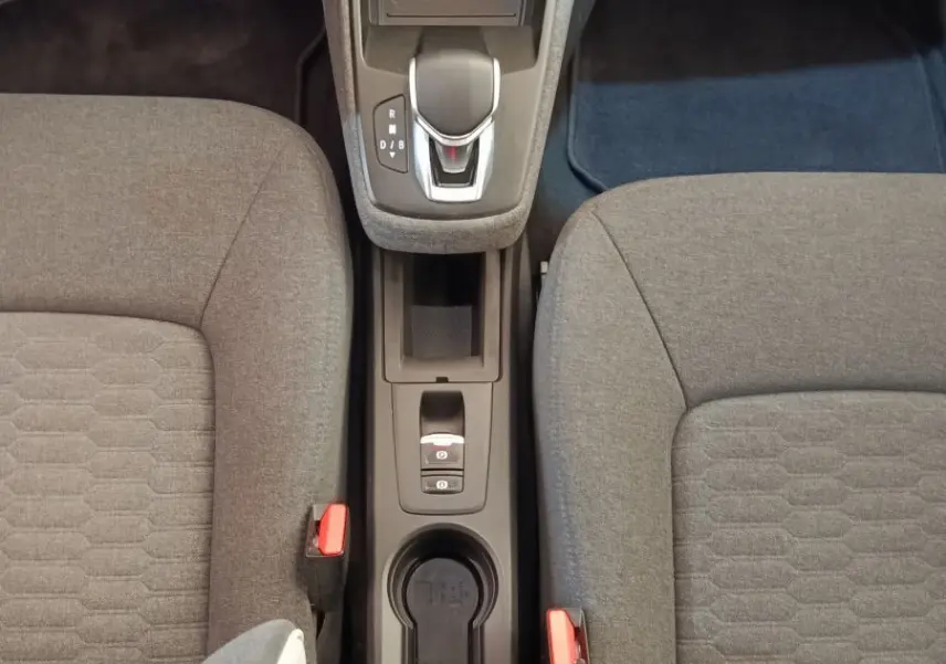 Vue plongeante sur la console centrale et les sièges gris du Renault ZOE Zen R135 blanc, avec levier de vitesses automatique.