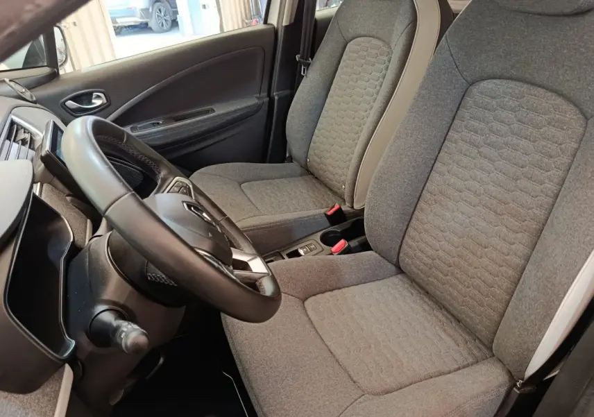 Vue intérieure côté conducteur de la Renault ZOE Zen 2021, volant cuir synthétique et sièges gris texturés.