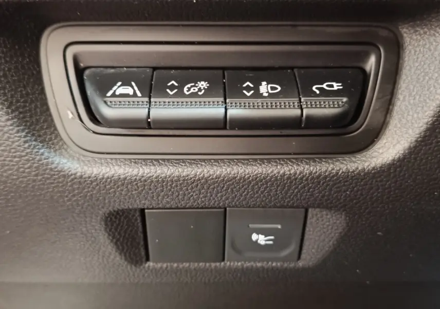 Gros plan sur les boutons de commande noirs du tableau de bord de la Renault ZOE blanche, version Zen R135.