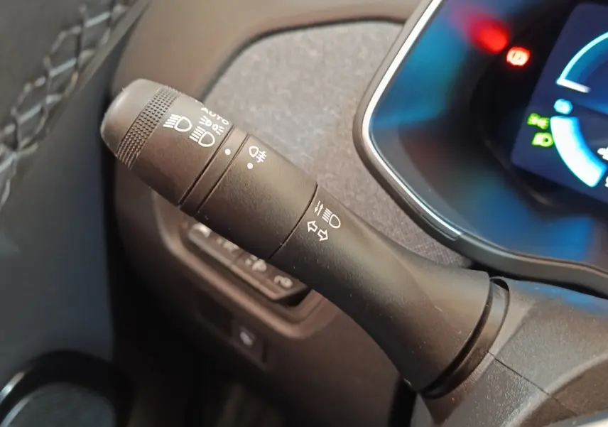 Gros plan sur la manette de commandes des phares et clignotants dans l'habitacle noir du Renault ZOE blanc 2021.