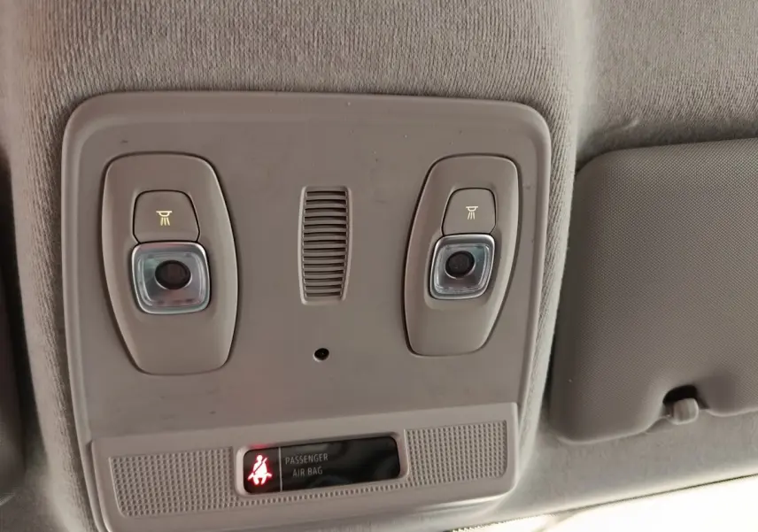 Vue intérieure du plafonnier gris clair avec éclairages et témoin airbag passager allumé dans une Renault ZOE blanche.