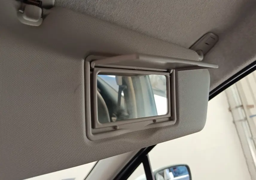 Miroir de courtoisie ouvert sur pare-soleil côté conducteur dans l'habitacle d'une Renault ZOE blanche 2021.