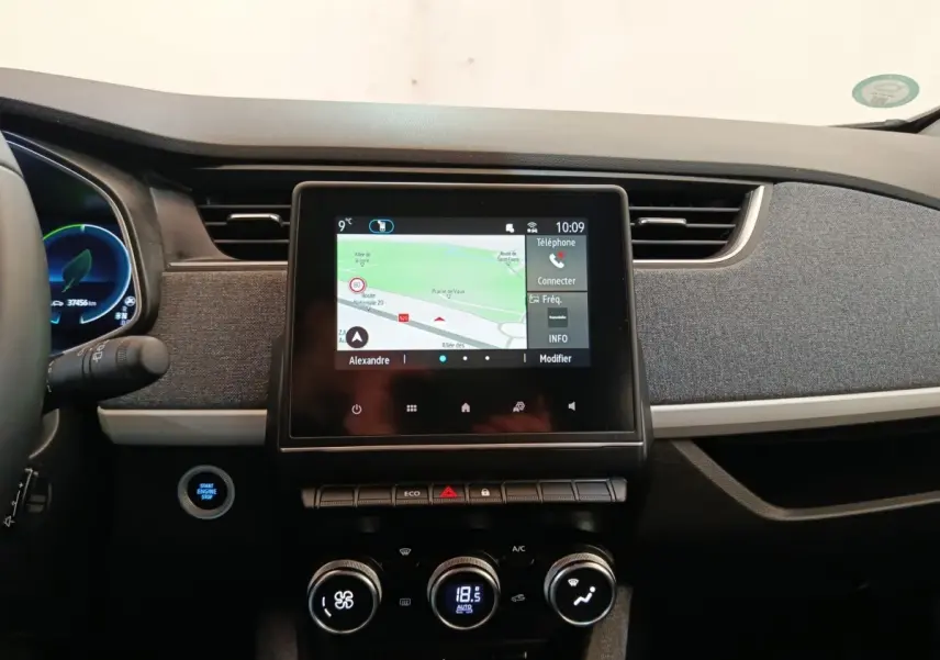 Tableau de bord central de Renault ZOE blanc, vue frontale sur l'écran tactile et commandes climatisation.