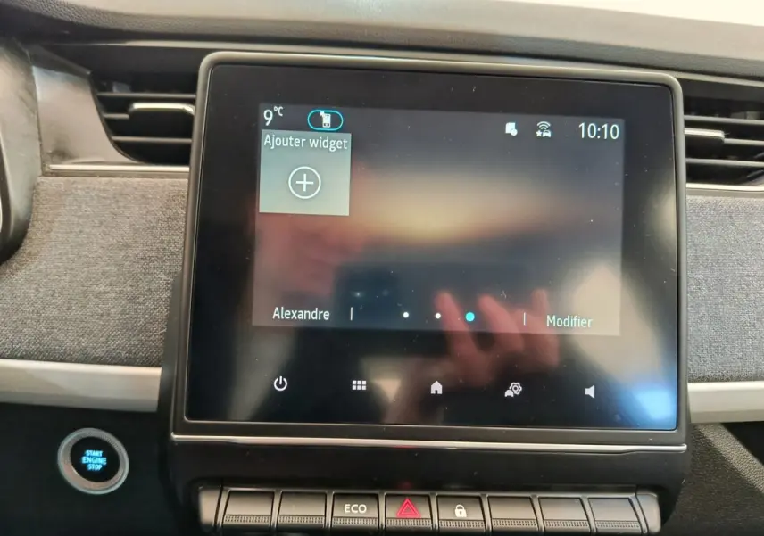 Écran tactile central allumé et bouton démarrage bleu dans l’habitacle de la Renault ZOE Zen blanche de 2021.