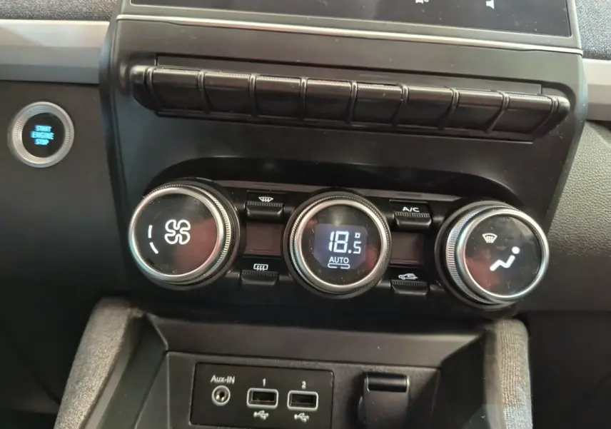 Gros plan sur la console centrale de la Renault ZOE blanche 2021, montrant les commandes de climatisation et le bouton start/stop.