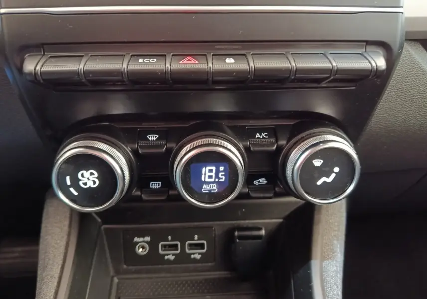 Gros plan sur la console centrale de la Renault ZOE blanche, montrant les commandes de climatisation et les ports USB.