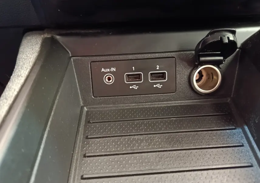 Gros plan sur les prises USB, Aux-IN et prise 12V dans le rangement avant de la Renault ZOE Zen R135 blanche de 2021.