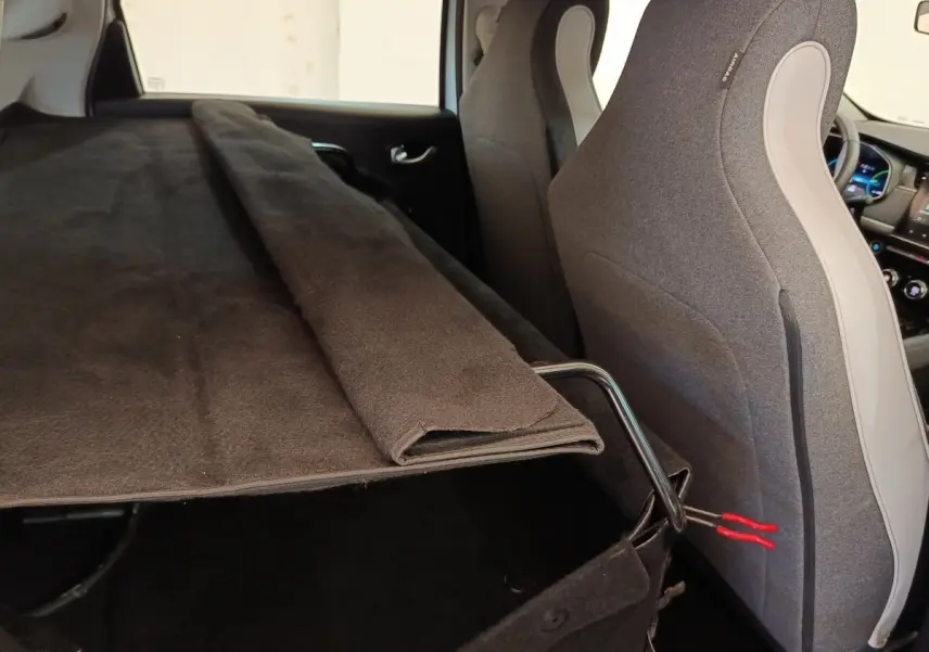 Vue intérieure arrière droite de la Renault ZOE blanche, montrant la banquette rabattue et le coffre partiellement couvert.