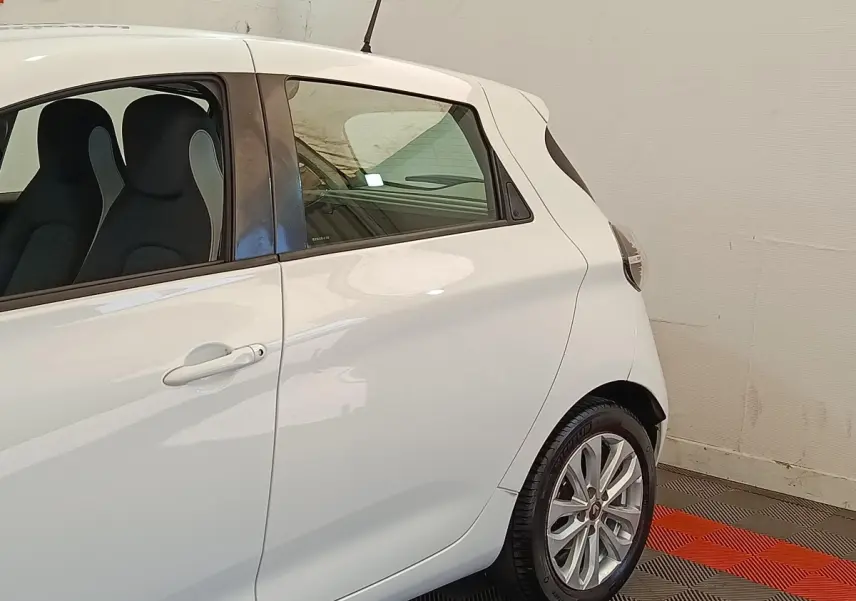 Vue latérale côté gauche d'une Renault ZOE blanche 2021, avec jantes alliage et vitres teintées.