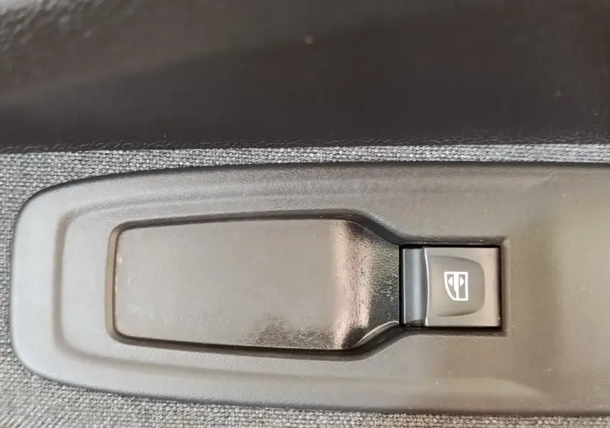 Gros plan sur le bouton de commande de lève-vitre électrique côté conducteur de la Renault ZOE blanche Zen R135 2021.