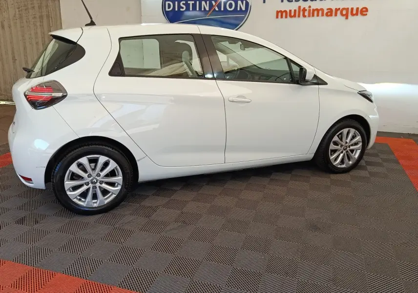 Profil droit de la Renault ZOE blanche 2021, version Zen R135, sur sol damier avec jantes alliage visibles.