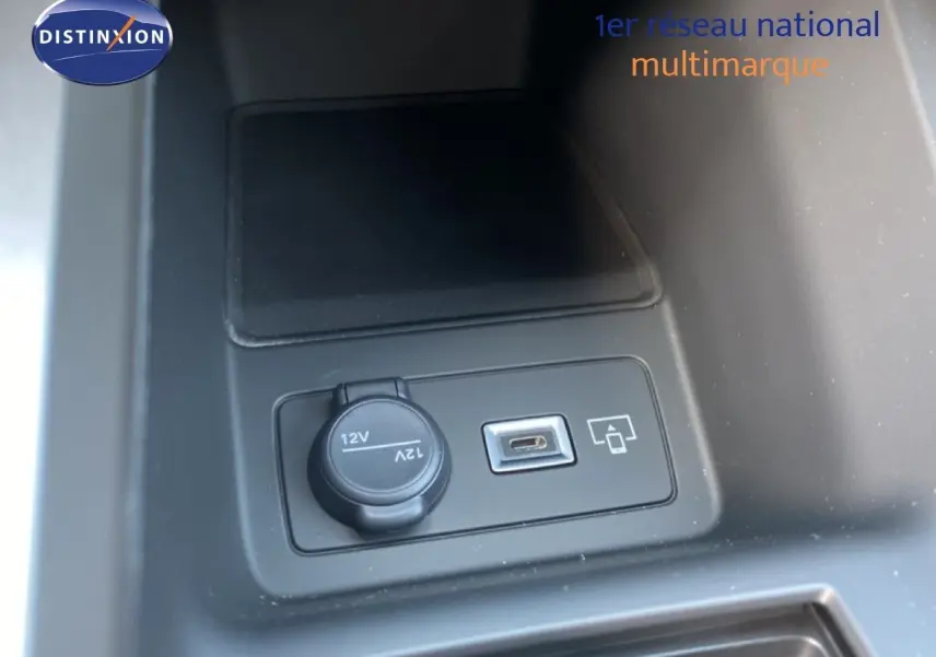 Gros plan sur la prise 12V et port USB intégrés dans la console centrale d'une Peugeot 308 Hybrid blanche.