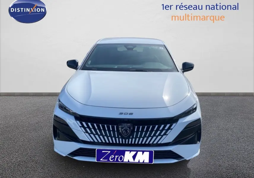 Vue avant d'une Peugeot 308 Hybrid 145ch GT blanche Okenite Metal avec calandre distinctive et logo lion central.