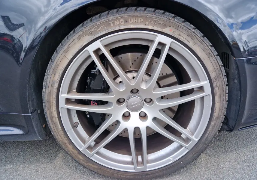 Gros plan sur la roue avant droite d'une Audi RS6 Avant noire de 2009 avec jante alliage et étrier de frein RS visible.