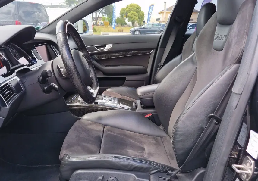 Vue intérieure côté conducteur de l'Audi RS6 Avant noire de 2009, sièges sport en cuir avec logo RS6 embossé.