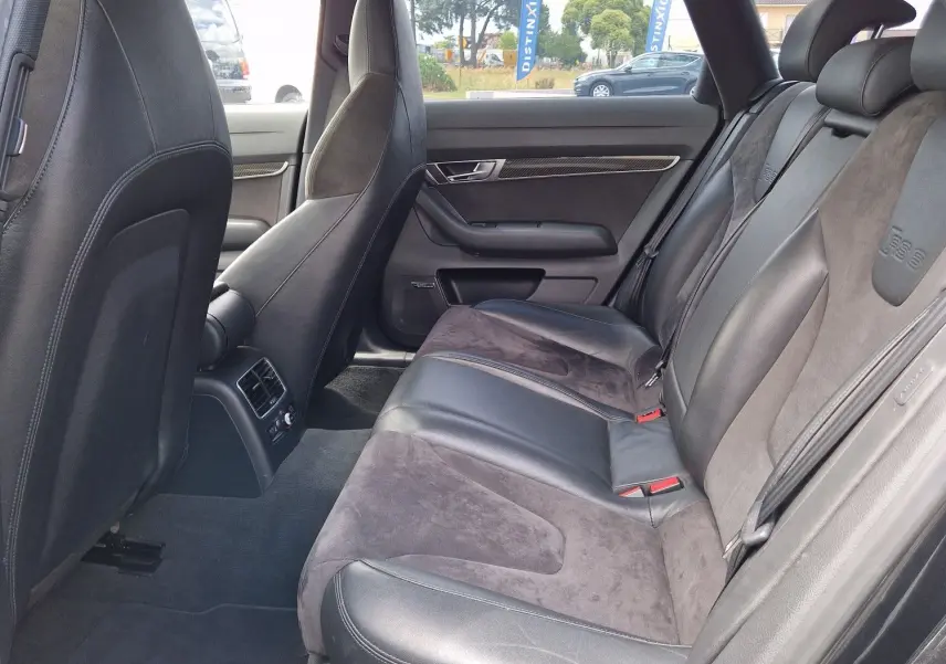 Vue intérieure côté arrière droit de l'Audi RS6 Avant 2009 noire, montrant les sièges en cuir et alcantara avec logo RS6 embossé.