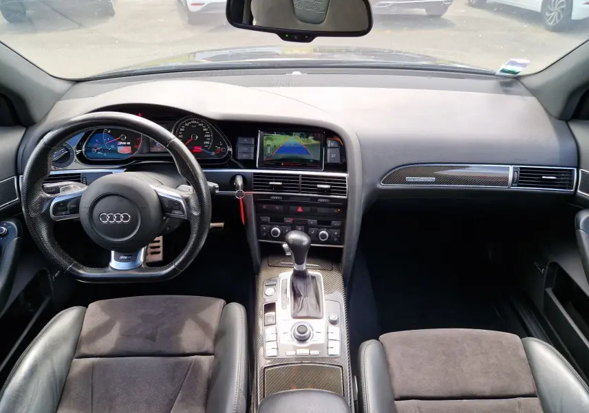 Vue intérieure avant de l'Audi RS6 Avant 2009 noire, avec tableau de bord, volant sport et console centrale en carbone.