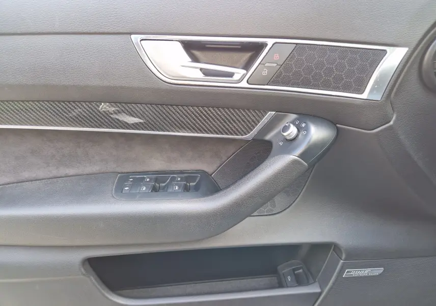 Détail de la porte côté gauche de l'Audi RS6 Avant noire de 2009, avec insert carbone et haut-parleur Bose intégré.
