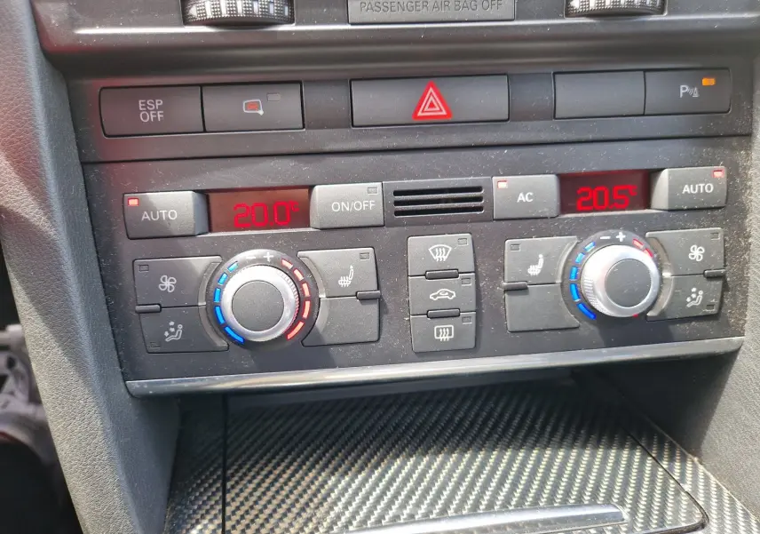 Vue rapprochée de la console centrale de l'Audi RS6 Avant 2009, montrant les commandes de climatisation bi-zone avec affichage digital rouge.