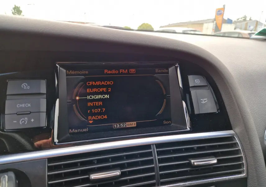 Vue intérieure du tableau de bord de l'Audi RS6 Avant 2009, écran radio FM affichant plusieurs stations, finition noire.