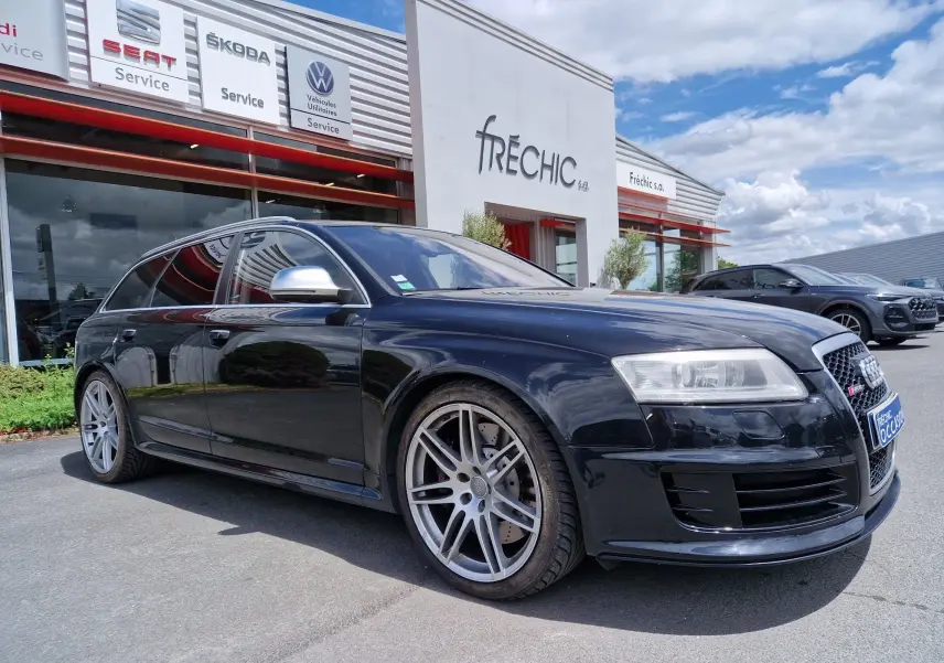 Audi RS6 Avant noire vue en 3/4 avant droit, avec jantes alliage et calandre RS distinctive, stationnée devant un garage.