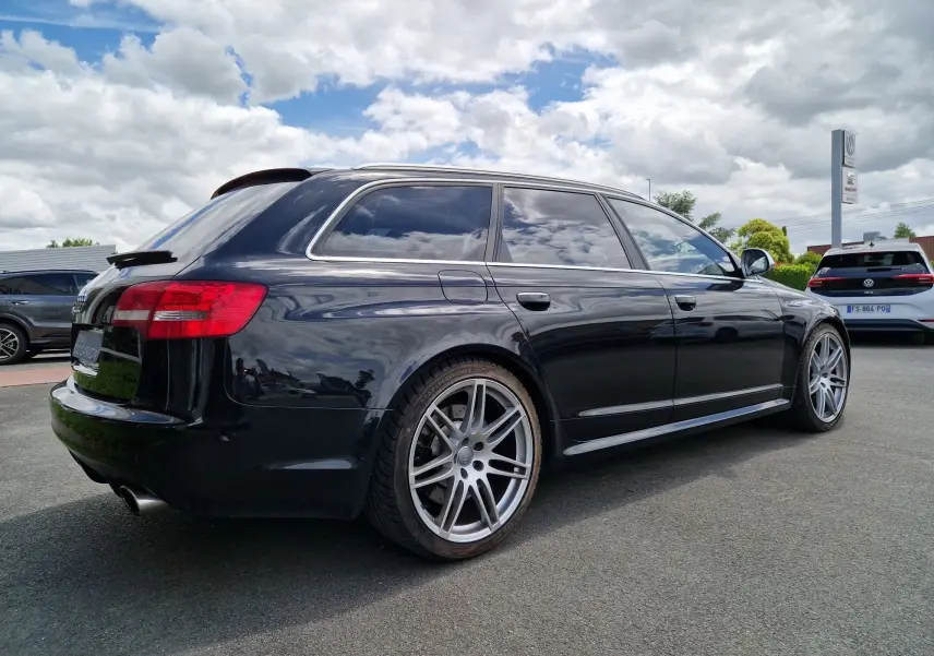Audi RS6 Avant noir vue 3/4 arrière droit, mettant en valeur ses jantes alliage et ses vitres teintées.
