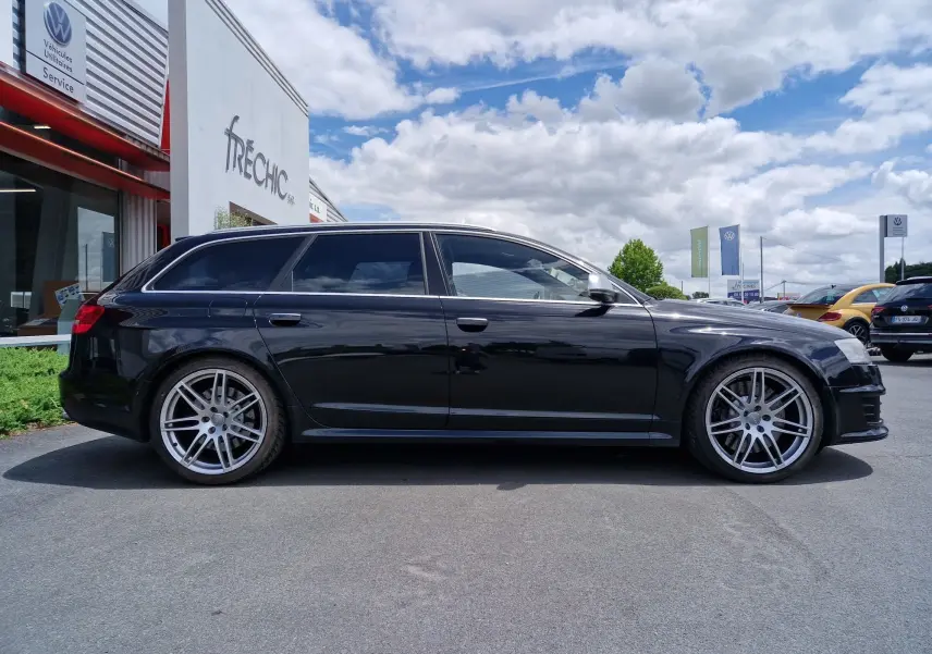 Audi RS6 Avant noire vue de profil côté gauche, avec jantes alliage sport et vitres teintées, stationnée en extérieur.