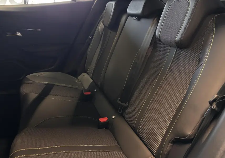 Vue latérale intérieure des sièges arrière noirs avec surpiqûres vertes du Peugeot 2008 1.2i Hybrid GT 2025.