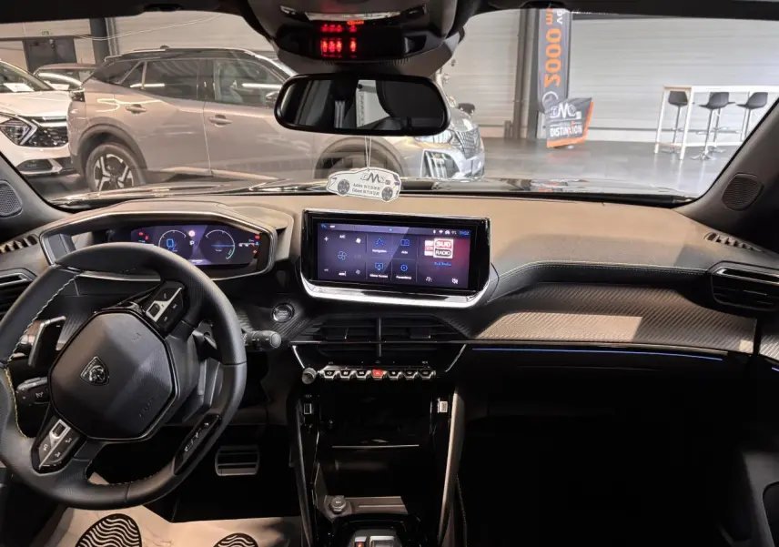Vue intérieure avant du Peugeot 2008 blanc 2025, tableau de bord moderne avec écran tactile et volant compact cuir.