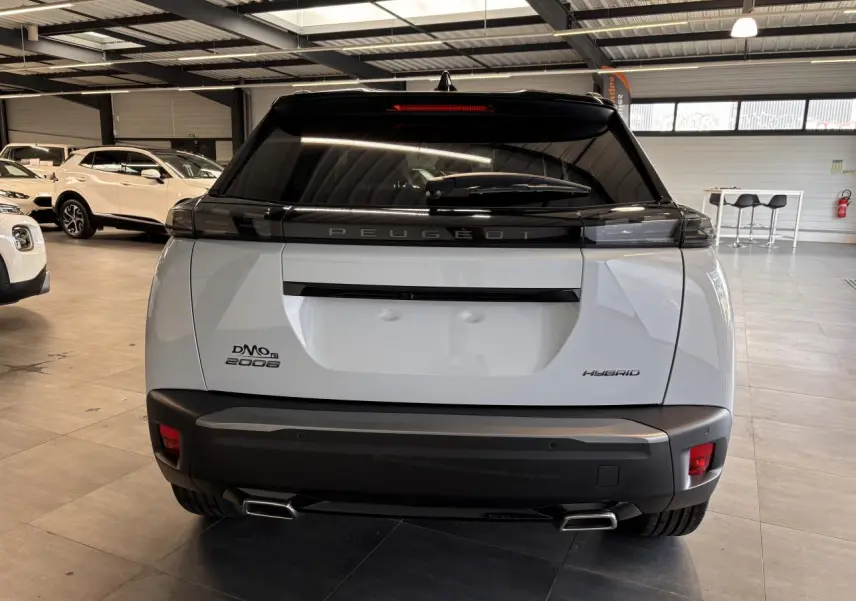 Vue arrière d’un Peugeot 2008 blanc hybride 2025 avec toit noir et double sortie d’échappement chromée.