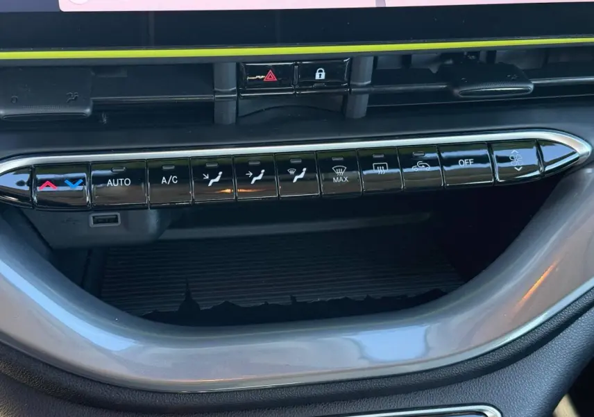 Gros plan sur la console centrale de la Fiat 500 e 95ch MY24, avec commandes climatisation et bande décorative jaune.