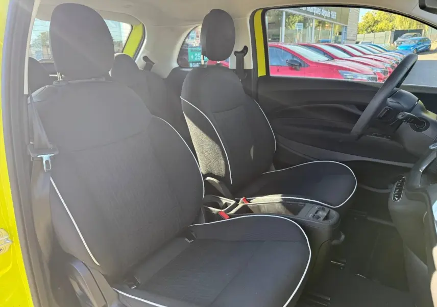 Vue intérieure côté conducteur de la Fiat 500 électrique jaune 2024 avec sièges noirs et volant multifonction.
