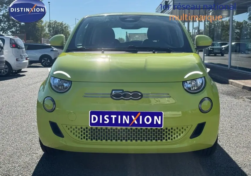Vue frontale d'une Fiat 500 électrique jaune Amalfi, avec logo 500 et phares ronds visibles au soleil.