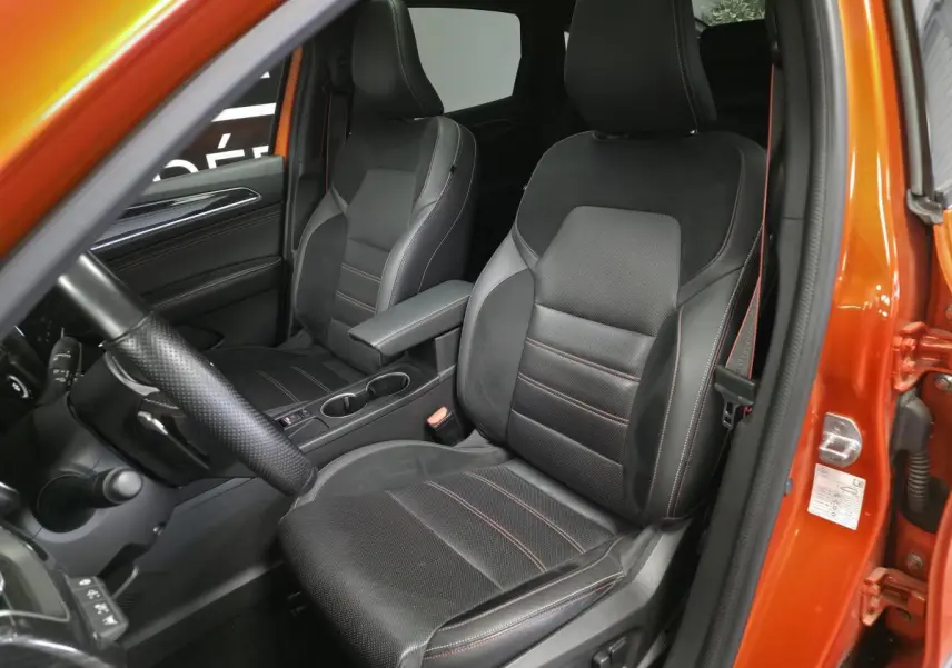 Vue intérieure côté conducteur du Renault Arkana orange, sièges sport cuir/suédine noirs avec surpiqûres rouges.