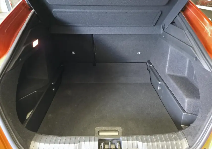 Coffre ouvert vu de l'arrière d'un Renault Arkana orange Valencia, montrant un espace de rangement propre et spacieux.