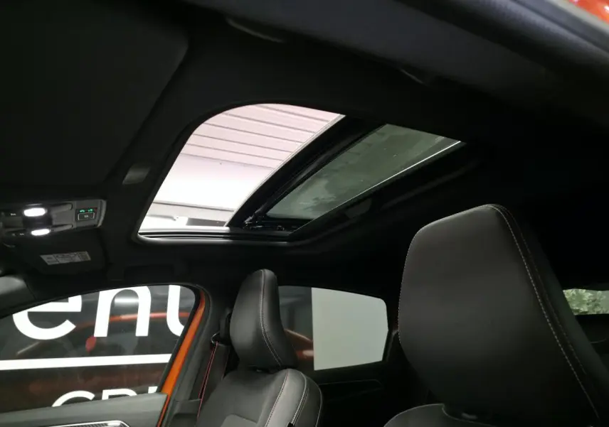 Intérieur du Renault Arkana 2024 avec toit ouvrant électrique et sièges avant cuir/suédine noirs surpiqués rouges.