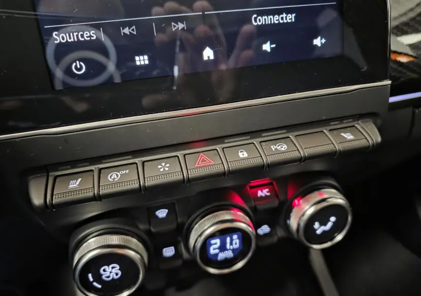 Gros plan sur la console centrale du Renault Arkana orange 2024, avec commandes climatisation et écran tactile visible.