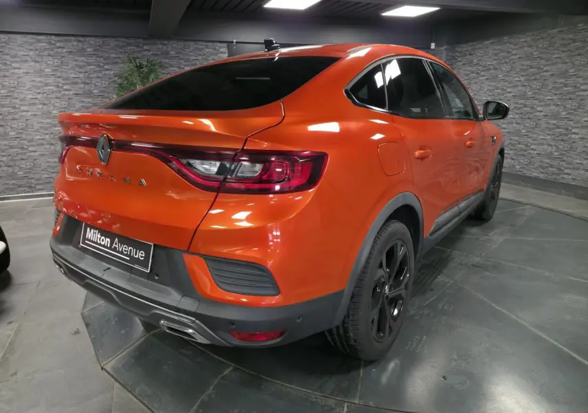 Vue 3/4 arrière droite d'un Renault Arkana orange Valencia avec jantes noires et toit ouvrant électrique visible.