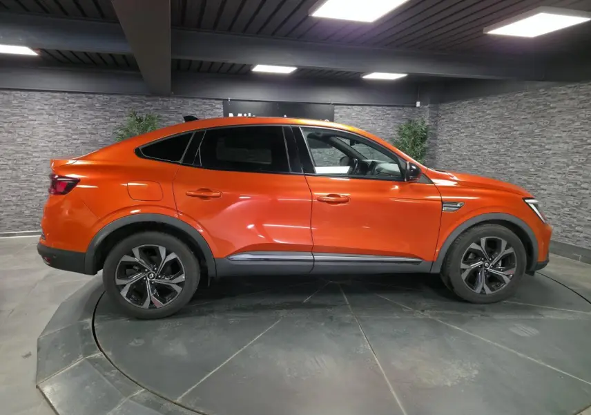Profil droit du Renault Arkana 2024 en Orange Valencia avec jantes R.S. Line et toit ouvrant électrique visible.