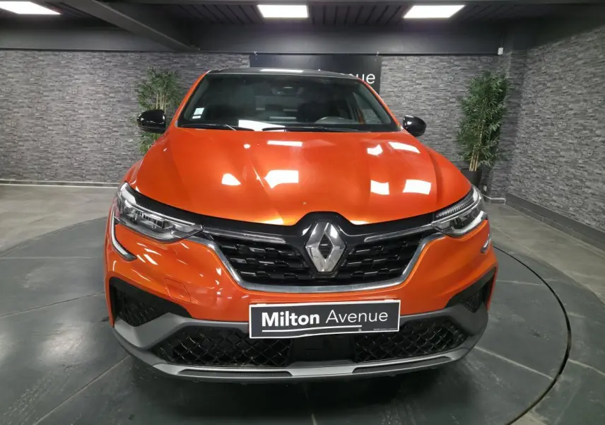 Vue frontale d'un Renault Arkana 2024 orange Valencia avec calandre noir brillant et badge R.S. Line visible.