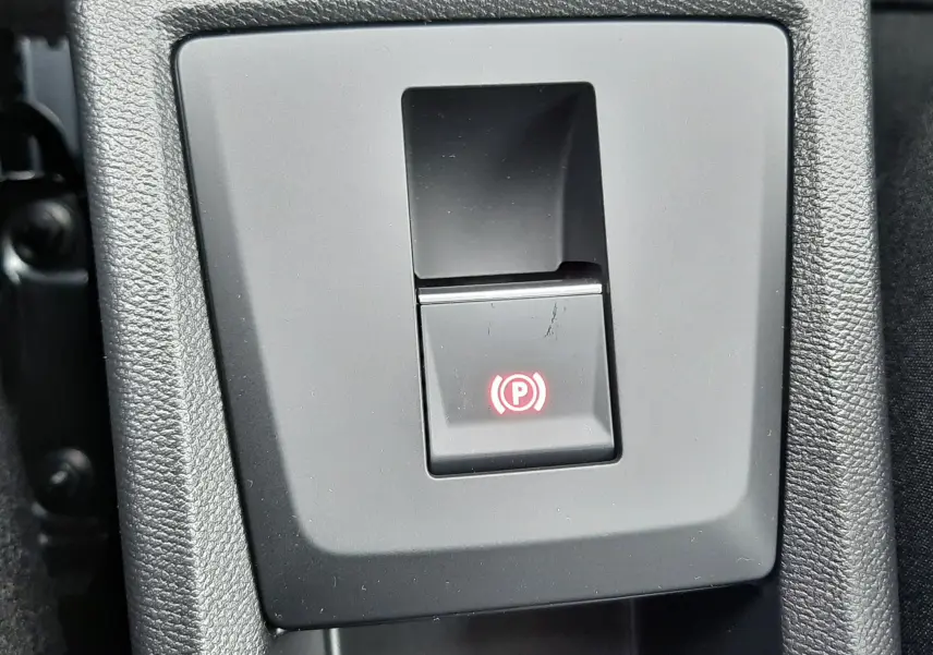 Bouton de frein à main électrique allumé sur la console centrale d'une Citroën C3 Aircross gris Mercury toit noir.